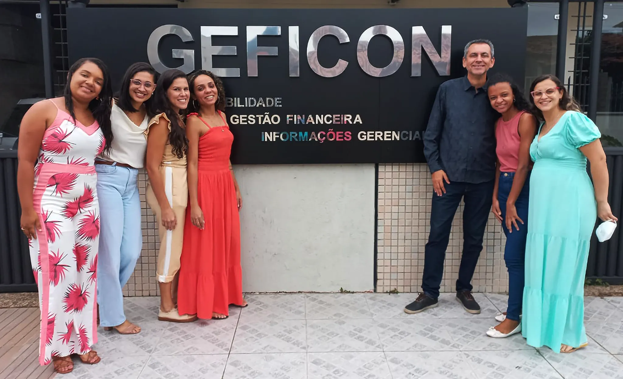 Equipe da Geficon em frente à fachada do escritório, com a placa Contabilidade, Gestão Financeira e Informações Gerenciais